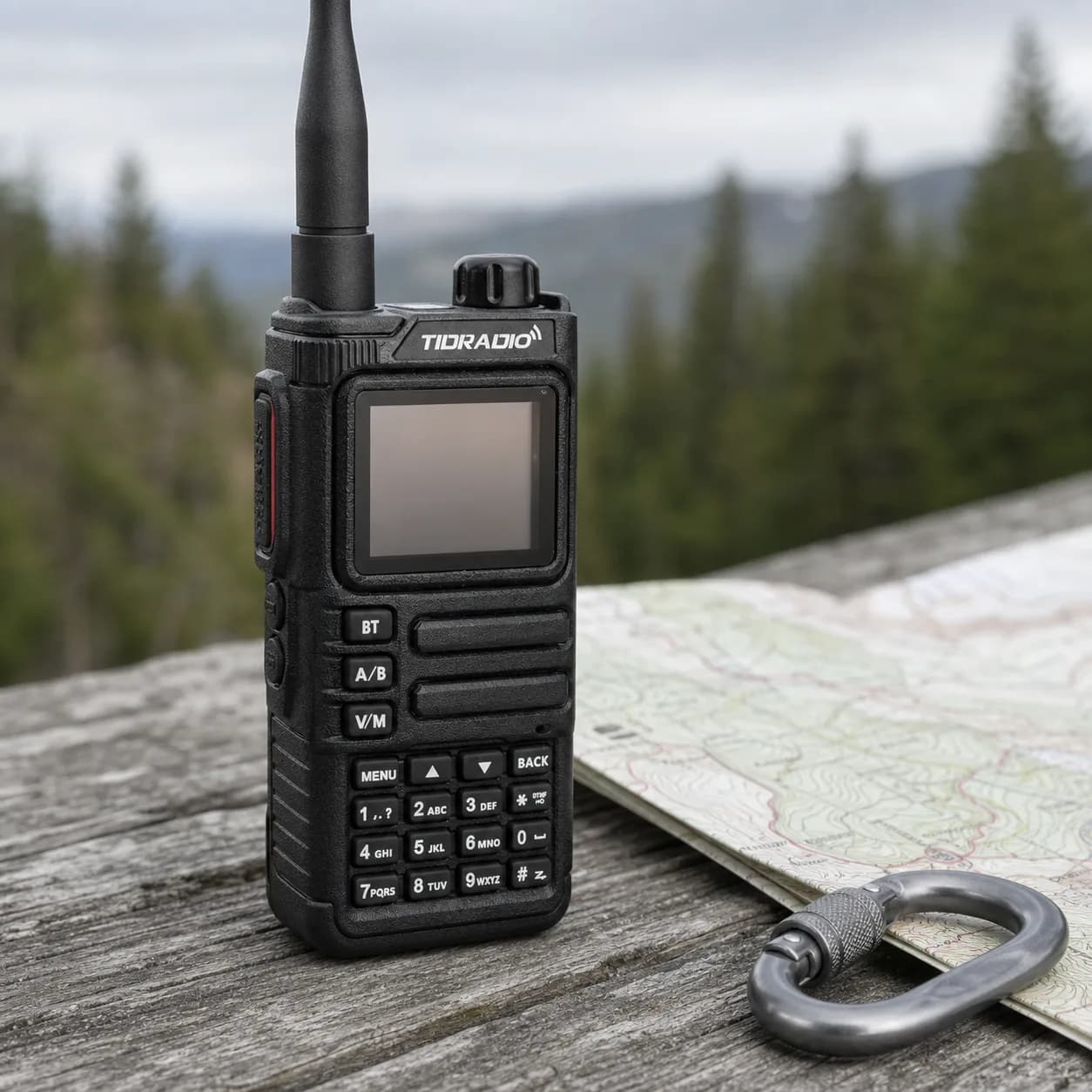 TIDRADIO TD-H9 handheld radio standing on weathered wood beside a topographic map and a carabiner