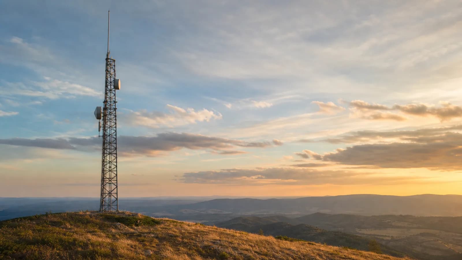 A VHF/UHF repeater antenna tower on a ridge against an open sky at golden hour